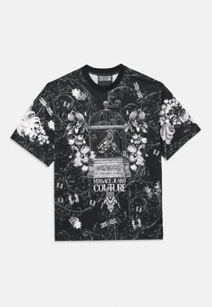 T-shirt noir à manches courtes avec des motifs floraux et de cages à oiseaux blancs, portant le texte "VERSACE JEANS COUTURE" en bas.