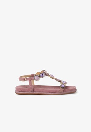 Vaaleanpunaiset mokkanahkasandaalit, joissa on litteä pohja. Nauhassa on koristeellisia violetteja ja kultaisia yksityiskohtia sekä säädettävä nilkkahihna.