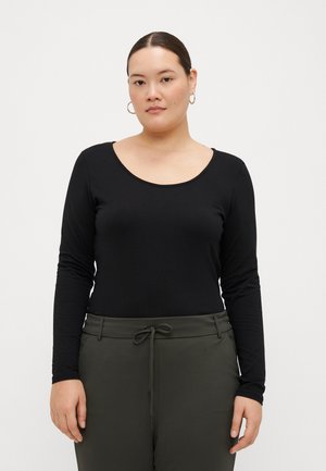 Top negro de manga larga con un escote redondeado, hecho de material suave, combinado con pantalones verdes con cordón. Tejido plano, diseño ajustado.