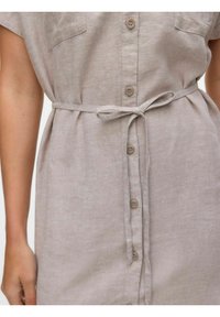Hellbeiges Leinenhemdkleid mit kurzen Ärmeln, Knopfverschluss vorne, zwei Brusttaschen und einem Stoffgürtel in der Taille für eine verstellbare Passform.