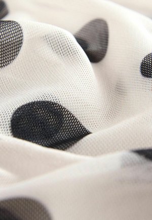 Przezroczysty materiał siateczkowy o białym tle w duże czarne kropki. Tekstura jest miękka i lekko przezroczysta.