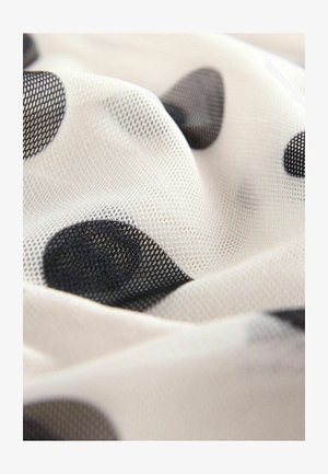 Przezroczysty materiał siateczkowy o białym tle w duże czarne kropki. Tekstura jest miękka i lekko przezroczysta.