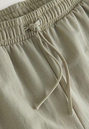 Lys olivengrønne shorts lavet af blødt, tekstureret stof, med elastik i taljen, snøre og subtile syningsdetaljer.