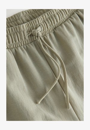 Lys olivengrønne shorts lavet af blødt, tekstureret stof, med elastik i taljen, snøre og subtile syningsdetaljer.