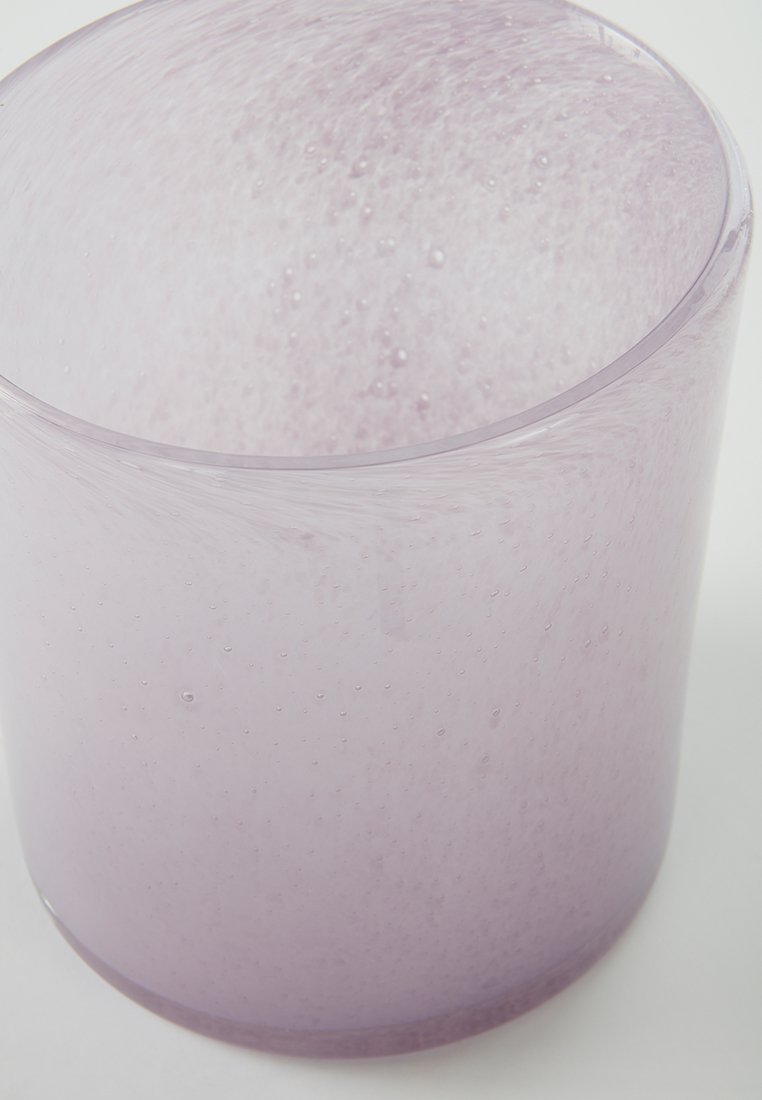 Vase en verre translucide de couleur violet clair, en forme cylindrique avec une surface texturée présentant de petites bulles et un bord lisse.