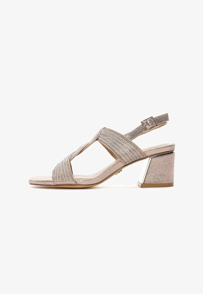 Pale pink heeled sandal with a T-strap design, embellished with narrow metallic bands and a geometric block heel. Buckle closure at ankle.