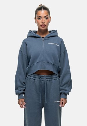 Gray cropped hoodie with zip closure and large hood, featuring the text "GOODFORNOTHING" on the chest, paired with matching drawstring sweatpants.