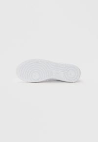 Valge kummist tennisetossude tald, millel on ringikujulised ja horisontaalsed mustrid. Sile tekstuur ja puhas disain, minimaalsete brändi elementidega.