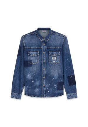 Denimshirt in medium blauw met een vervaagde uitstraling, twee borstzakken, zilveren metalen knopen en variërende blauwe patchworkaccenten. Witte spikkels aanwezig.