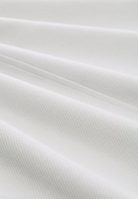 Tessuto bianco con una sottile trama diagonale, drappeggiato in morbide pieghe, che mette in risalto una superficie tessuta liscia.