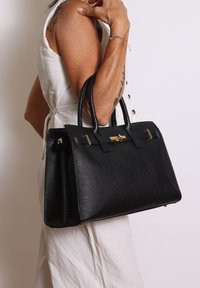 Zwarte leren handtas met een gestructureerde afwerking, strakke vorm, dubbele handvaten en gouden hardware accenten. Voorzien van een sluiting met een klipsluiting aan de voorkant.
