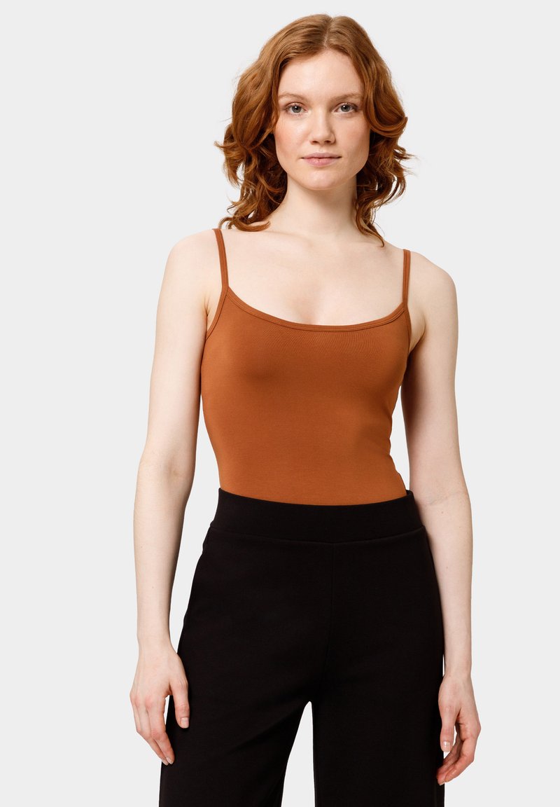 Brown fitted camisole with thin straps, made from a smooth fabric, paired with high-waisted black pants. The design is simple and streamlined.