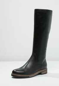Botte noire en cuir, hauteur genoux, avec une finition lisse, un bout rond, un petit talon en bois et des détails de couture minimalistes. Convient à diverses tenues.