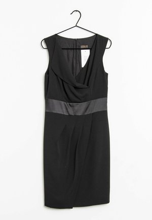 Mouwloze zwarte jurk met gedrapeerde halslijn en satijnen tailleband, hangend aan een zwarte hanger met een wit prijskaartje eraan.