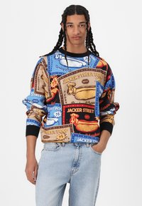Colorful sweatshirt featuring a collage of food-themed graphics. Made of soft fabric with a relaxed fit, ribbed cuffs, and a round neckline.