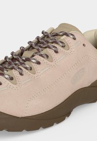 Chaussure de randonnée en daim rose clair avec lacets marron à motifs, languette couleur tabac et semelle en caoutchouc marron, logo cousu sur le côté.