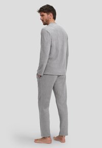 Conjunto de loungewear de felpa gris que incluye una camiseta de manga larga y pantalones con bolsillos. Textura suave y corte relajado, adecuado para uso en interiores.