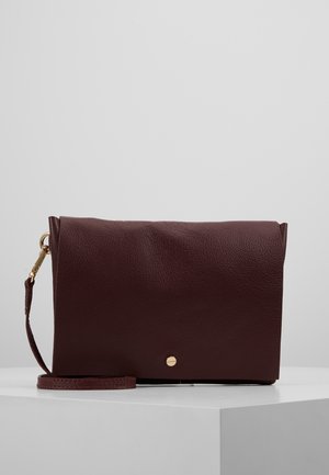 Bordowa damska torebka na ramię ze skóry o fakturowanej powierzchni, z klapką na zakładkę, złotymi ozdobami i odpinanym paskiem.