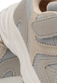 Zapatillas beige y gris con paneles de gamuza y malla, suela blanca gruesa y cierre de tira de Velcro.