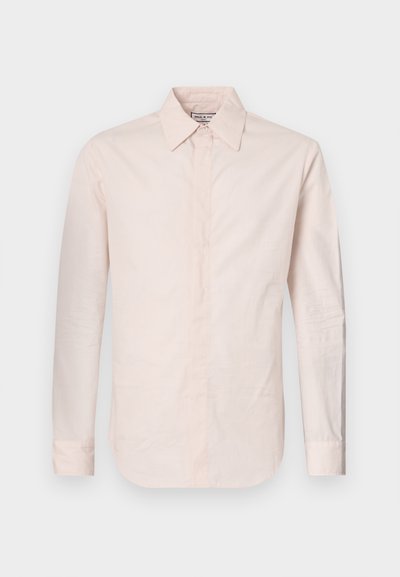 Chemise à manches longues rose clair en tissu lisse, dotée d'un collier pointu, d'une fermeture à boutons et d'un ourlet légèrement courbé.