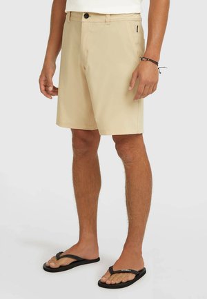 Khaki shorts gemaakt van lichtgewicht stof, met een standaard pasvorm, een ontwerp met vijf zakken en een knoopsluiting. Draagt zwarte slippers.