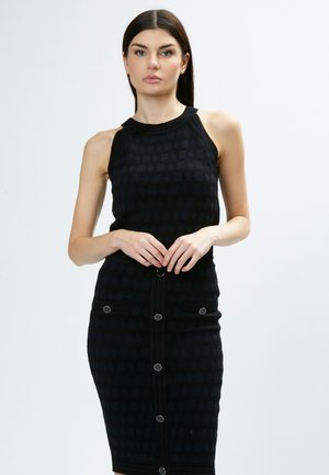 Abito nero a maglia con silhouette aderente, design senza maniche e finitura testurizzata. Presenta due tasche frontali e bottoni circolari lungo la parte anteriore.