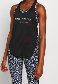 Černý sportovní tílko s logem "PINK SODA SPORT", které má síťový design. Spárované s přiléhavými legínami s bílým a černým geometrickým vzorem.