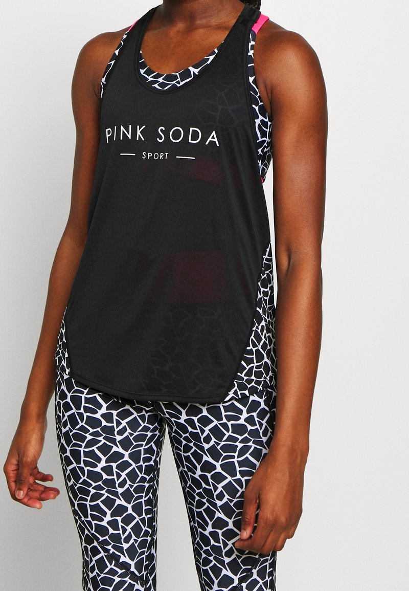 Černý sportovní tílko s logem "PINK SODA SPORT", které má síťový design. Spárované s přiléhavými legínami s bílým a černým geometrickým vzorem.