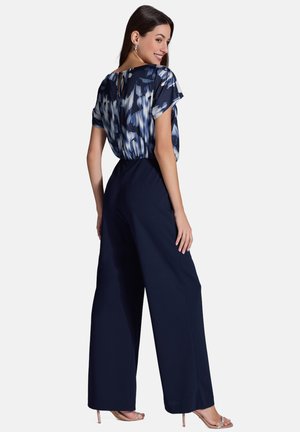 Pantalones de pierna ancha en azul marino combinados con una blusa de manga corta de patrón azul y blanco. Incluye un detalle de abertura en la parte posterior y una textura de tela suave.