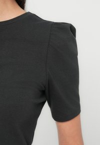 Zwart T-shirt met korte mouwen, een geribde ronde hals en opgepofte schoudernaden, gemaakt van een glad, rekbaar katoenweefsel.