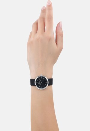 Schwarzes Lederarmbanduhr mit einem runden schwarzen Ziffernblatt, silberner Hardware und minimalistischen Stundenmarkierungen. Einfaches und elegantes Design an der Hand.