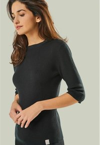 Schwarzer, gerippter Strickpullover mit Dreiviertelärmeln, rundem Halsausschnitt und subtilen Markenlabel-Details am Saum. Glatte Textur.