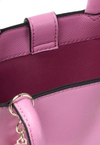 Sac à main en cuir rose avec un extérieur texturé, un intérieur lisse en bordeaux et des finitions noires. Dispose d'une boucle en métal pour attacher des accessoires.