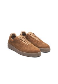 Brown suede sneakers with a low-top design, featuring a rounded toe, lace-up closure, and textured rubber outsole.
