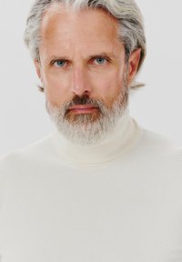 Sweter golf w kolorze kremowym, wykonany z prążkowanej tkaniny. Posiada wysoki kołnierz i dopasowany krój, podkreślający fakturę i gładką powierzchnię.