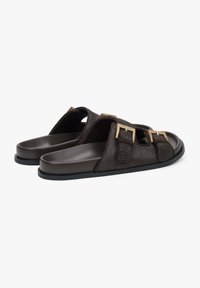 Brown slip-on sandals with a textured upper, featuring two gold-tone buckles and a smooth, matching sole.