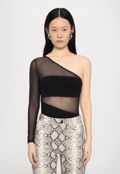 Bodysuit noir à une épaule avec panneau transparent, associé à un pantalon ajusté à motif serpent dans des tons beiges et gris. Texture lisse, design moderne.