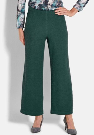 Groene gestructureerde wijde broek met een elastische tailleband, gecombineerd met grijze hoge hakken. De stof heeft een verhoogd patroon.