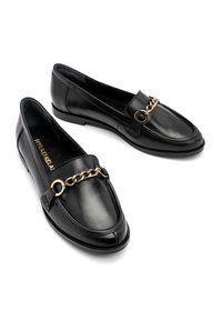 Black leather loafers featuring a gold chain accent, rounded toe, and a smooth texture. The design has minimal stitching details.