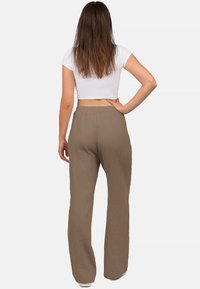 Braune gestreifte weite Hosen aus leichtem Stoff, mit einem elastischen Bund und einer lockeren Passform. Crocked weißes Oberteil sichtbar.
