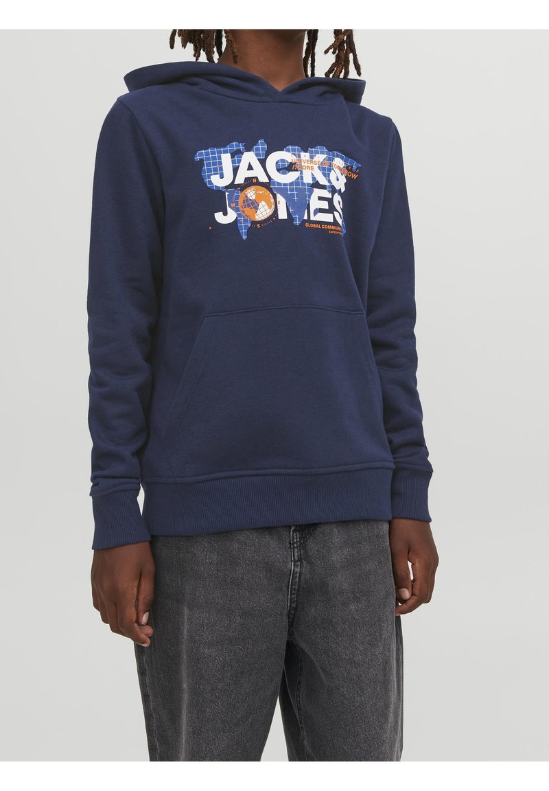 Námořnická modrá mikina s kapucí a přední kapsou, bílé a oranžové nápisy "Jack & Jones" nad modrou mapou světa, nošena s vybledlými černými džíny.