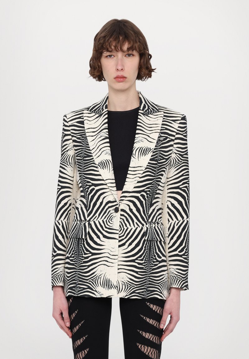 Zebra-mønstret blazer i sort og beige, struktureret design med skarpe slag, enknapslukning og to forlommer, fremhævende tekstureret stof.