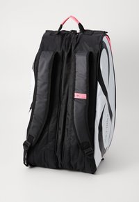Black and white backpack with padded adjustable straps, top handle, and a pink accent tag. Features a sleek, streamlined design and durable material.