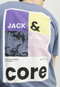 Kortärmad blå t-shirt i bomull med ett flerfärgat mönster: lila, gula och rosa rutor med svart text "JACK & JONES" och "core."