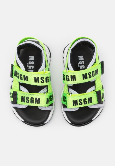 Sandálias pretas com correias ajustáveis em verde fluorescente com a marca "MSGM". O design inclui detalhes em branco e uma sola texturizada.