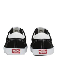Black suede sneakers with white leather accents, white rubber sole, and contrasting stitching. Features "VANS OFF THE WALL" branding on heel.