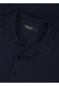 Marineblaues Polohemd aus strukturiertem Stoff, mit einer Knopfleiste mit drei schwarzen Knöpfen, kurzem Kragen und einem Etikett mit der Aufschrift "MAERZ MÜNCHEN".