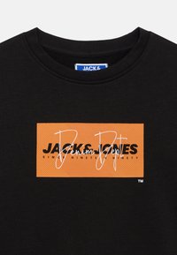 Μαύρο μπλουζάκι με ανάγλυφο πορτοκαλί ορθογώνιο γραφικό που αναγράφει "JACK & JONES" και "Denim Dept" με αντιθετικό μαύρο και λευκό κείμενο.