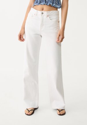 Hvide wide-leg jeans lavet af denim, med høj talje, forlommer og kobberfarvet hardware, parret med en cropped blå top.