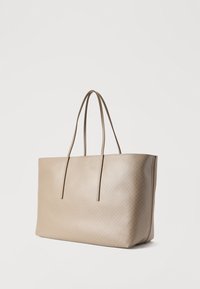 Μπεζ τσάντα tote με υφή ύφανσης, δύο μακριές λαβές και δομημένο σχήμα. Λείο φινίρισμα με μινιμαλιστικό σχεδιασμό.